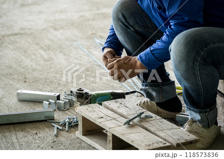 A builder works with screws and nuts on a wooden pallet 118573836