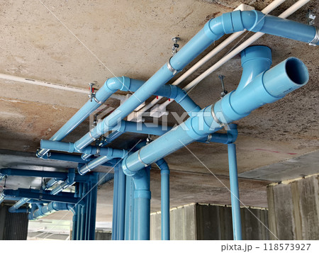 A bright blue pipes attached to a solid concrete wall A bright blue pipes attached to a solid concrete wall 118573927