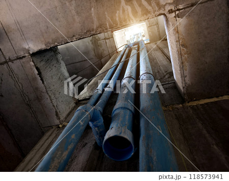 A bright blue pipes attached to a solid concrete wall 118573941