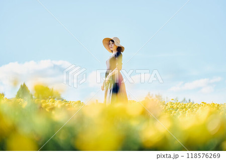 花畑で帽子をかぶって立つ女性 118576269