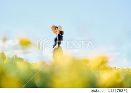 花畑で帽子をかぶって立つ女性 118576271