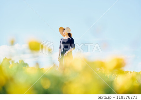 花畑で帽子をかぶって立つ女性 118576273