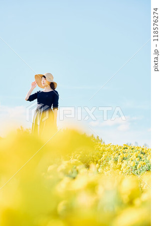 花畑で帽子をかぶって立つ女性 118576274