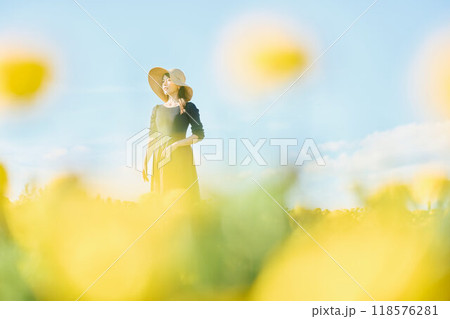 花畑で帽子をかぶって立つ女性 118576281