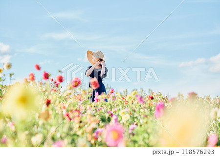 花畑で帽子をかぶって立つ女性 118576293