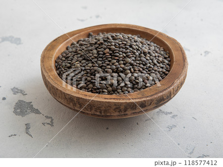 Raw dry black lentils seeds in wooden bowl on light table.Macro. 118577412