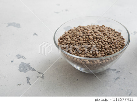 Raw dry white lentils seeds in glass bowl on light table.Macro. 118577413