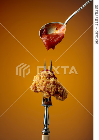 Fried chicken with ketchup on a fork. Fried chicken with ketchup on a fork. 118578280