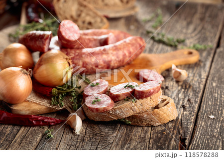 Dry-cured sausage with bread and spices on a old wooden table. 118578288