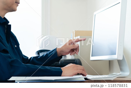 パソコンと資料を見比べる作業着の男性 118578831