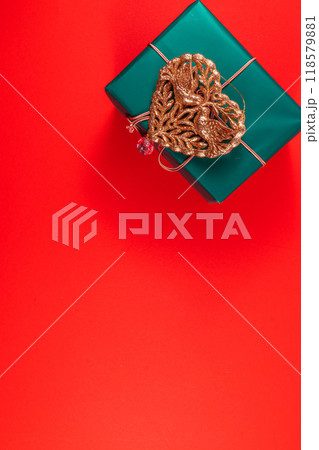 Banner green Christmas gift box with gold heart decoration on red background 118579881