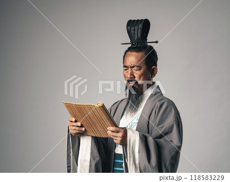 三国志に登場する諸葛孔明のような中国歴史上の人物が竹簡に書かれた文字を読むシーン 118583229