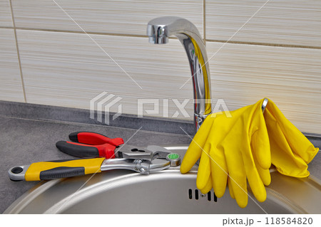Yellow rubber gloves and tools for replacing kitchen sink faucet aerator 118584820