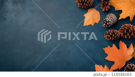 Autumn leaves and pine cones arranged on a dark blue background during the fall season 118588163