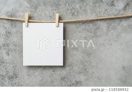 Blank white sheet hanging on twine against a textured gray wall in a minimalist setting 118588932