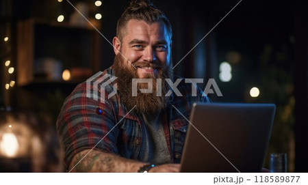 A man who has a beard is currently using a laptop computer 118589877