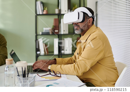 Senior Man Wearing Virtual Reality Headset in Office Setting 118590215