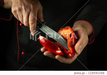 Cleaning bell pepper with knife in hands of chef. Concept on black background of cooking vegetable dish. Cutting red pepper Cleaning bell pepper with knife in hands of chef. Concept on black background of cooking vegetable dish. Cutting red pepper 118591588