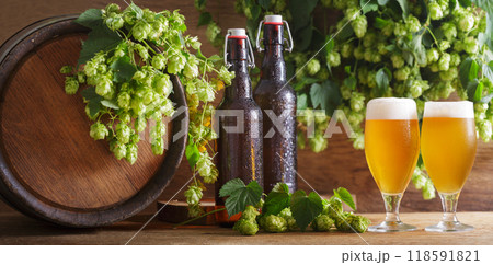 glasses of beer, green hops, bottles and beer barrel on wooden background glasses of beer, green hops, bottles and beer barrel on wooden background 118591821