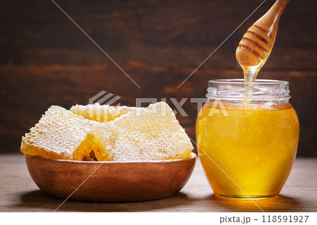 Fresh honey drips into jar of honey Fresh honey drips into jar of honey 118591927