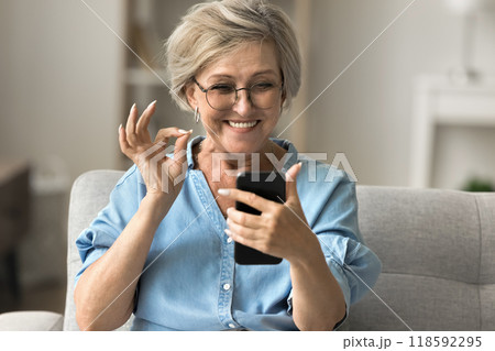 Happy mature woman looking at her smartphone showing okay gesture 118592295