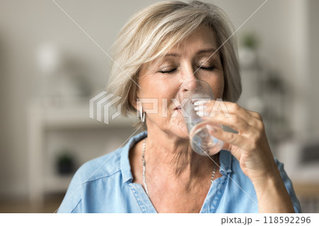 Closeup face older woman holding glass drinking still natural water 118592296