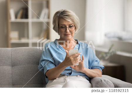 Attractive focused mature woman chatting online using modern smartphone 118592315