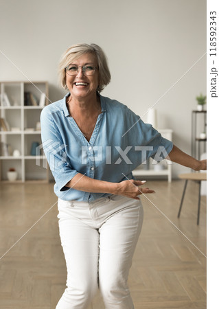 Lively energetic middle-aged woman in casual clothes dancing indoor 118592343