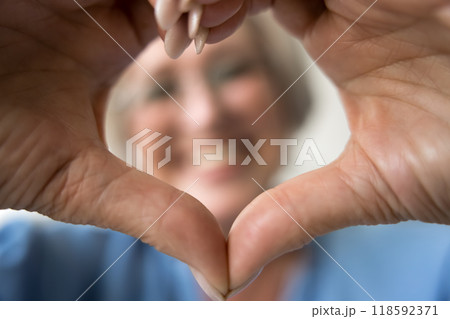 Closeup cropped view older woman showing symbol of love Closeup cropped view older woman showing symbol of love 118592371