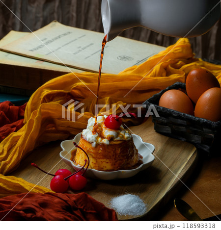 ホイップクリームとチェリーをトッピングしたプリンに、たっぷりのカラメルソースが注がれる瞬間 118593318