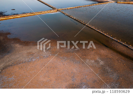 Aerial view of salt pans at sunset showcasing water and land contrast Aerial view of salt pans at sunset showcasing water and land contrast 118593629