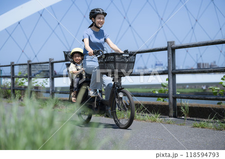青空の綺麗な道を自転車に乗るママと子供 ママチャリでお出かけや出勤 全身の広角 緑の前ボケあり 青空の綺麗な道を自転車に乗るママと子供 ママチャリでお出かけや出勤 全身の広角 緑の前ボケあり 118594793