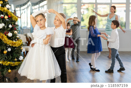 Little children practicing waltz dance in school-hall decorated with Christmas-tree Little children practicing waltz dance in school-hall decorated with Christmas-tree 118597159
