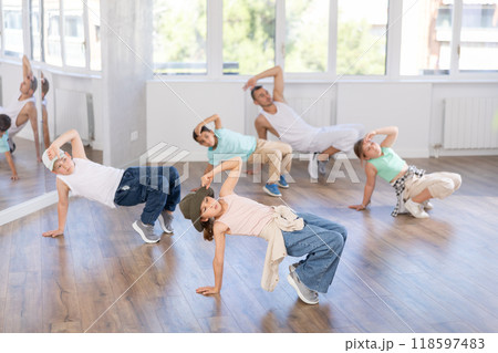 Happy girl and teens doing breakdance in dance hall with male trainer in choreography studio Happy girl and teens doing breakdance in dance hall with male trainer in choreography studio 118597483