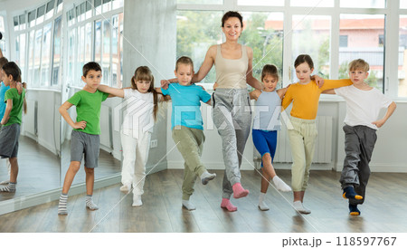 Group of children stand in row holding hands, performing Irish folk dance. 118597767