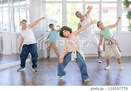 In sports studio, childrens team learns hip-hop dance accompanied by experienced man teacher 118597770