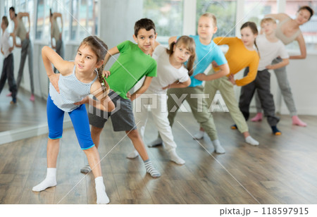 Children do warm-up exercises in studio, prepare for pair dance class Children do warm-up exercises in studio, prepare for pair dance class 118597915