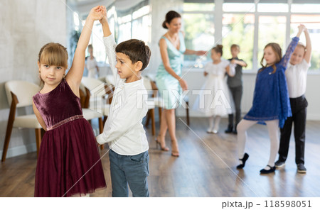 Little children in elegant dresses practicing waltz dance in school hall Little children in elegant dresses practicing waltz dance in school hall 118598051
