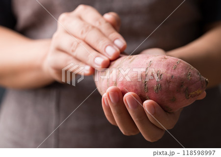 Raw organic Japanese sweet potatoes holding by hand 118598997