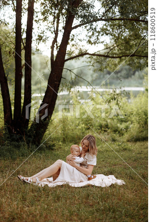 A woman is sitting on the grass with a baby in her arms 118600519