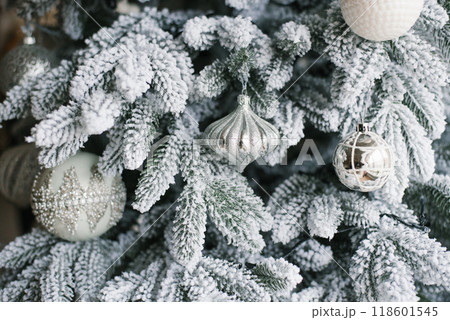 Christmas tree is covered in snow and the ornaments are of various shapes and sizes Christmas tree is covered in snow and the ornaments are of various shapes and sizes 118601545