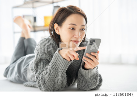 寝転んでスマホを見る女性 118601847