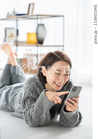 寝転んでスマホを見る女性 118601848