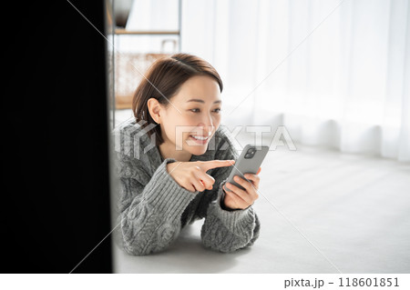 寝転んでスマホを見る女性 118601851