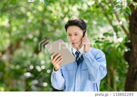 タブレットとスマホを持つ作業着の男性 118602293