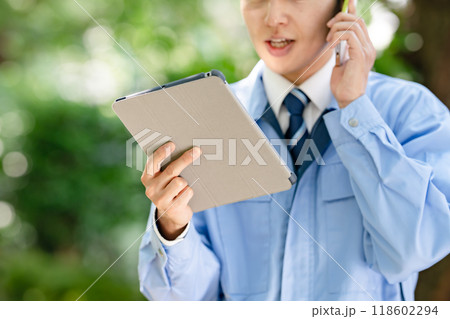タブレットとスマホを持つ作業着の男性 タブレットとスマホを持つ作業着の男性 118602294