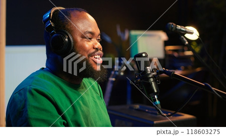 Young songwriter playing piano and singing on microphone, recording his new music and mixing the tunes on digital software. Musician composer producing soundtracks with modern gear. Camera A. 118603275