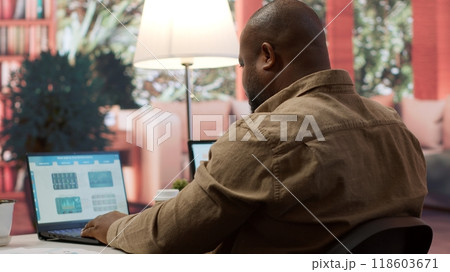Startup entrepreneur looking into project details on laptop at his home setup, reviewing budget numbers and solving business tasks to achieve enterprise growth objectives. Camera A. Startup entrepreneur looking into project details on laptop at his home setup, reviewing budget numbers and solving business tasks to achieve enterprise growth objectives. Camera A. 118603671