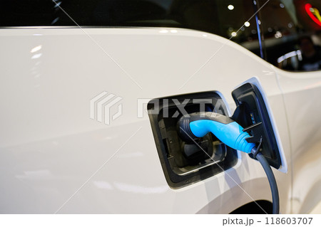 Close-up of electric vehicle charging at station. EV car with plugged-in cable recharging battery. Clean energy transportation 118603707
