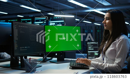 Admin in data center using mockup PC to design, implement and manage gear, ensuring optimal performance and reliability. Expert in server room coding on green screen computer, camera B 118603763